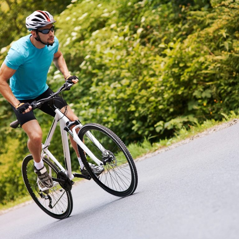 Un cycliste en tenue sportive ride sur une route entourée de verdure.